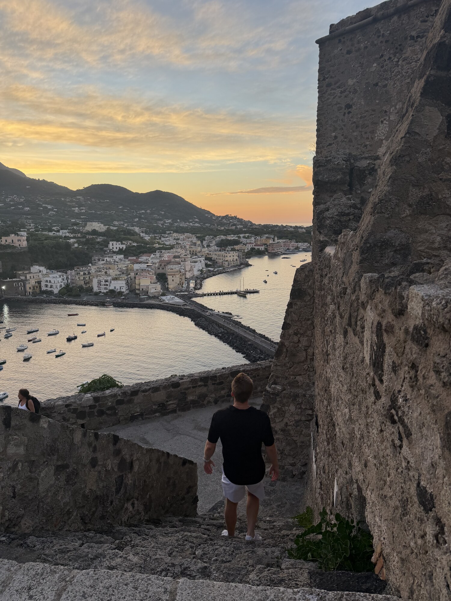 Mark Moholt looking out over a coastal town and bay through a stone archway